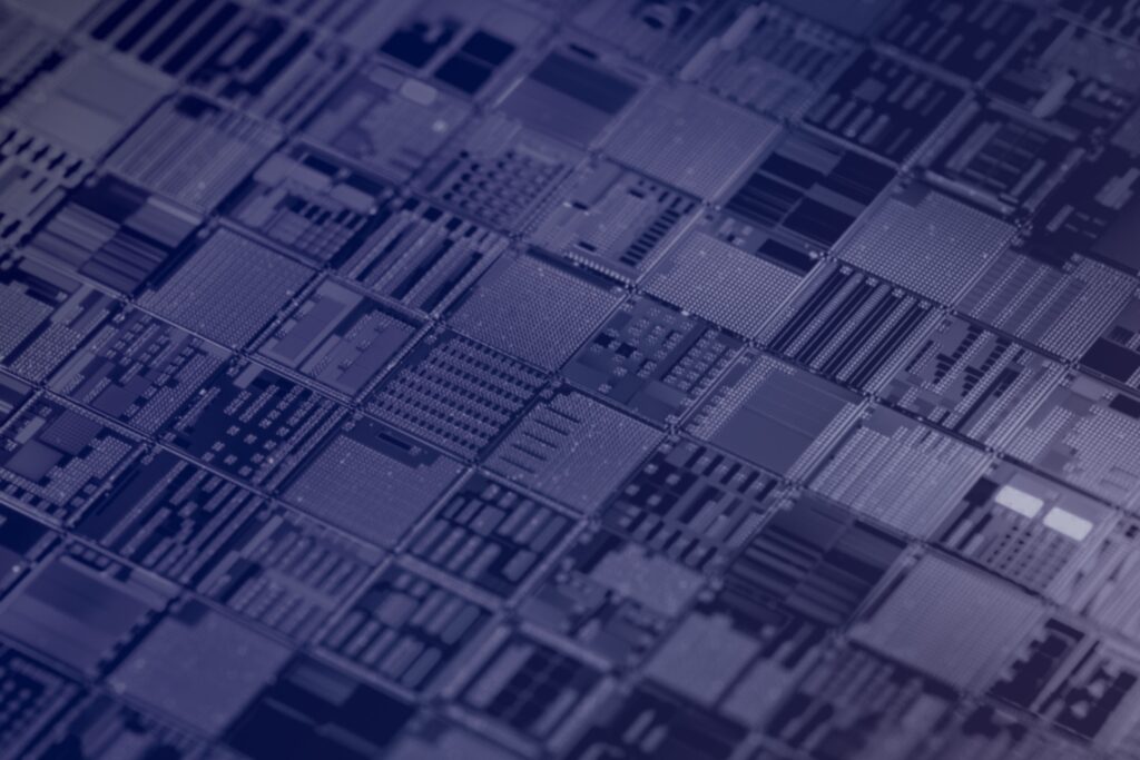 Close-up view of an array of computer microchips or circuit boards, showing intricate patterns, lines, and components arranged in a repetitive, grid-like structure under a blue-toned light.