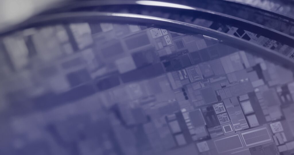 Close-up view of several silicon wafers with visible integrated circuit patterns, reflecting light in a high-tech, industrial setting. The image is predominantly blue and purple in tone.